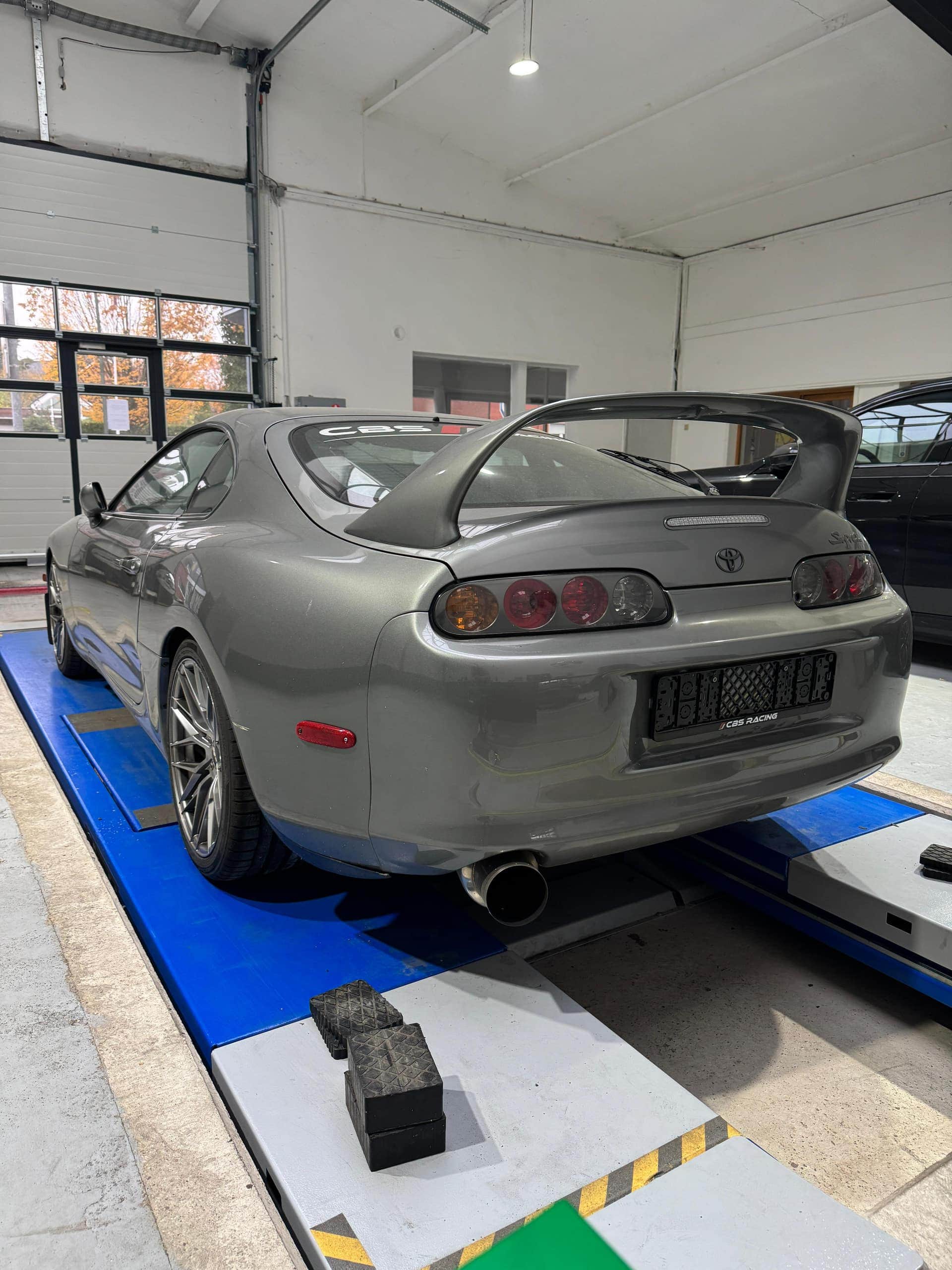Grauer Toyota Supra von hinten auf der blauen Hebebühne der Prüfhalle