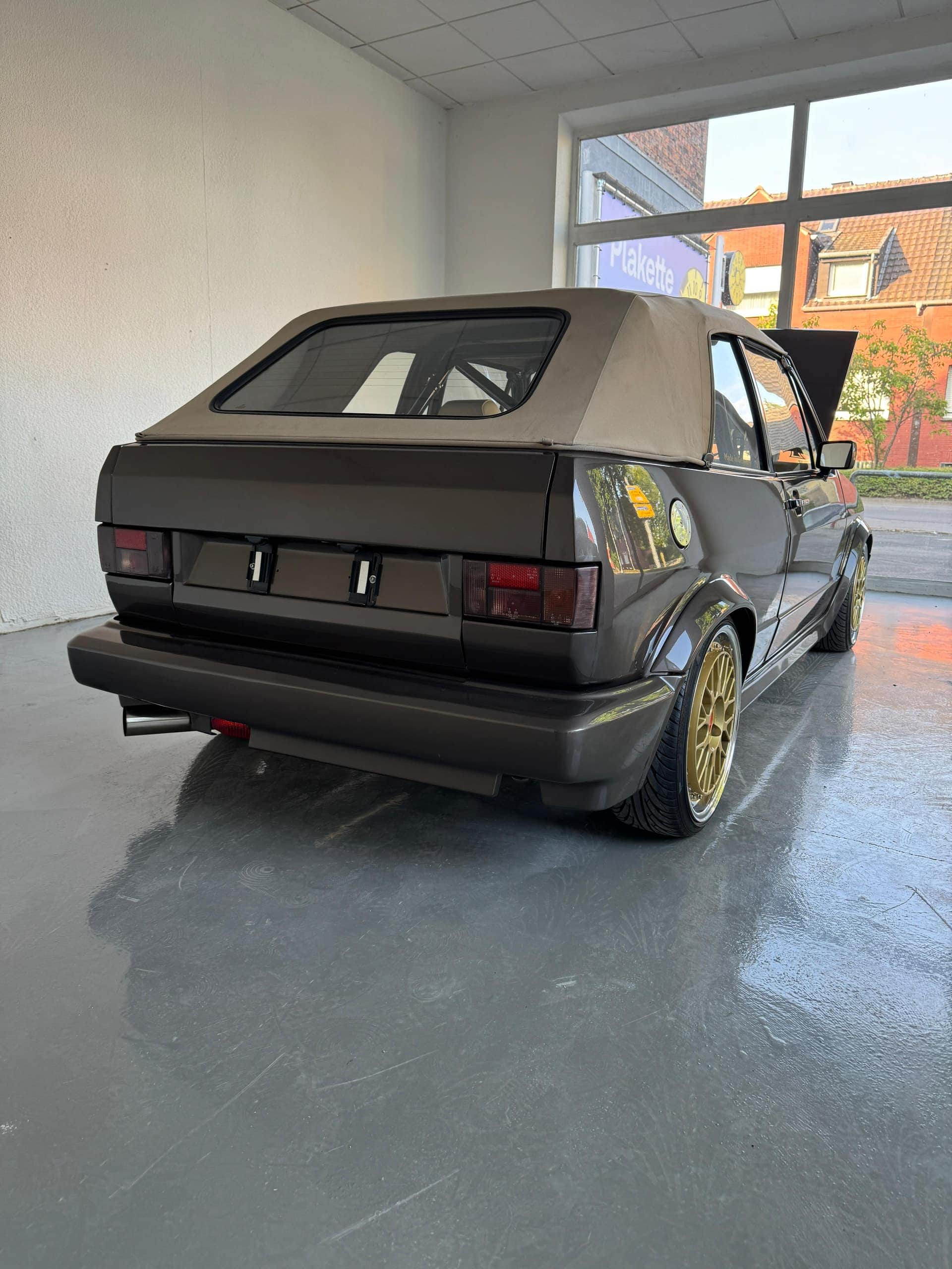 Brauner VW Golf 1 Cabrio mit beigem Verdeck und goldenen Felgen von schräg hinten