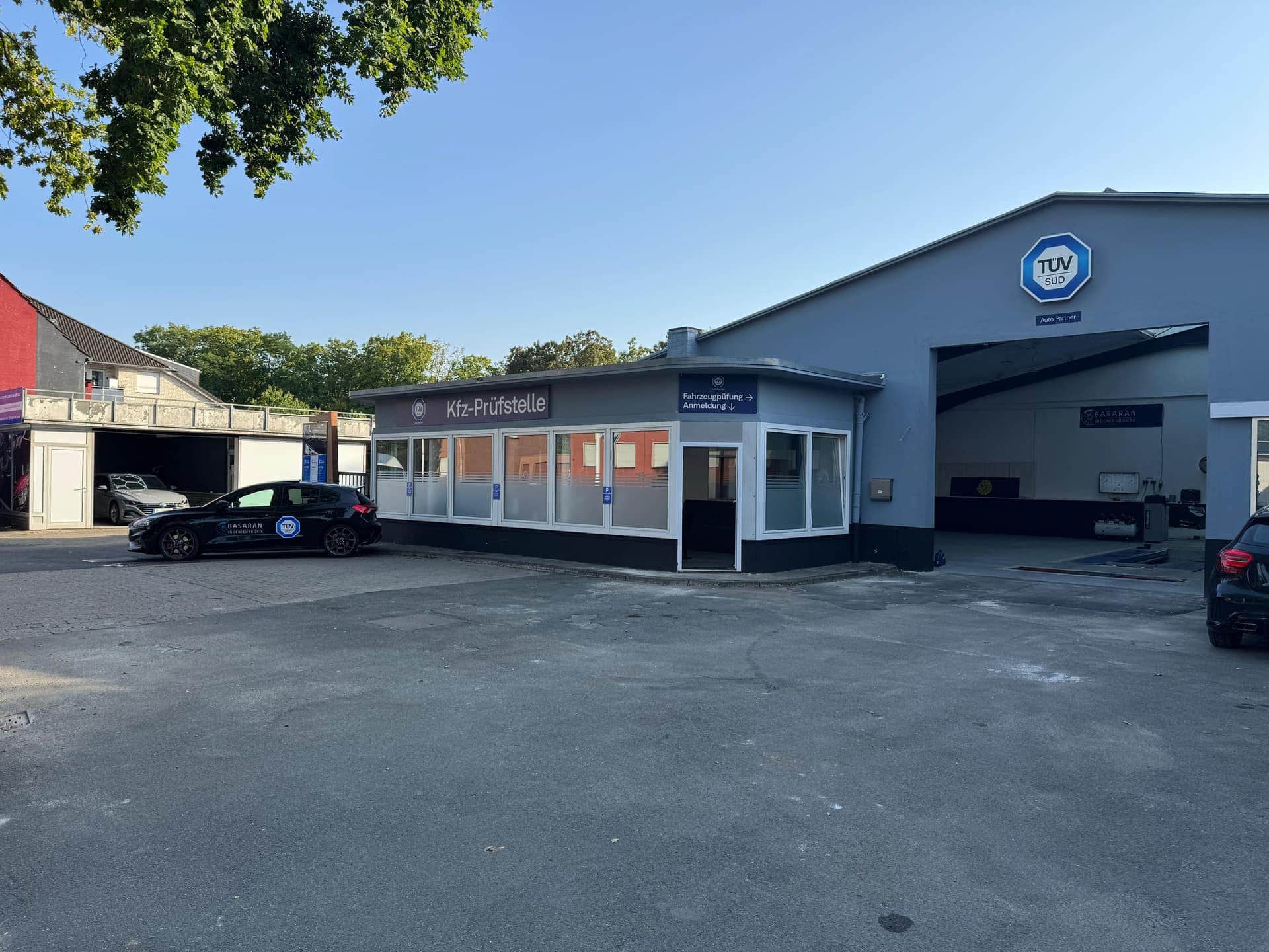 Betriebsgelände der Kfz-Prüfstelle Basaran in Ahlen mit Anmeldegebäude, offener Prüfhalle und Firmenfahrzeug